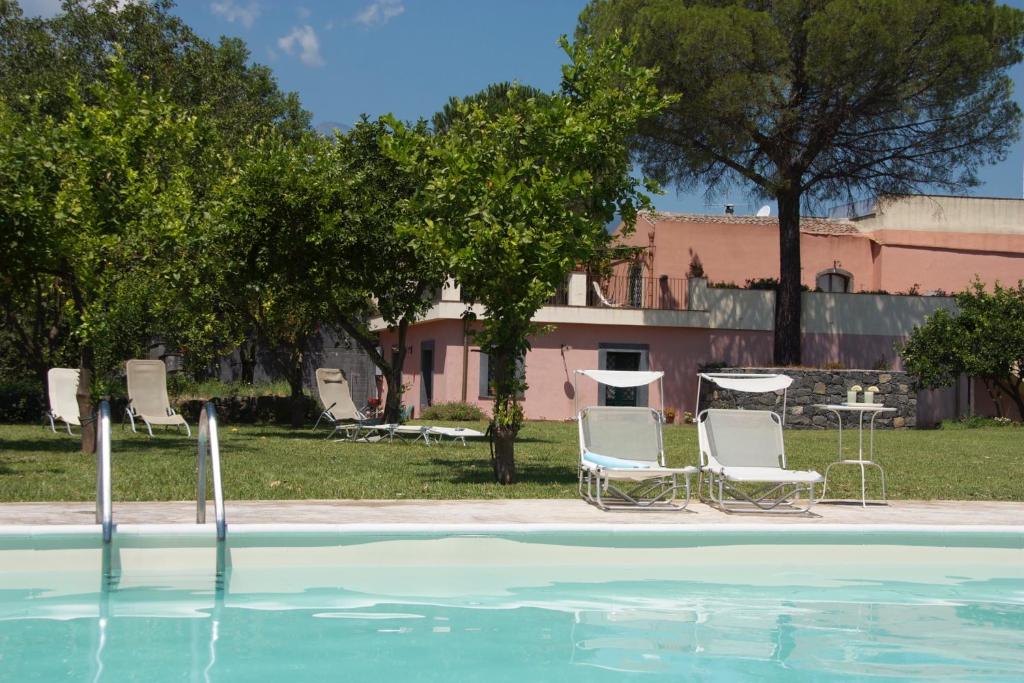 una piscina con sillas, una mesa y árboles en Agriturismo San Leonardello, en San Leonardello