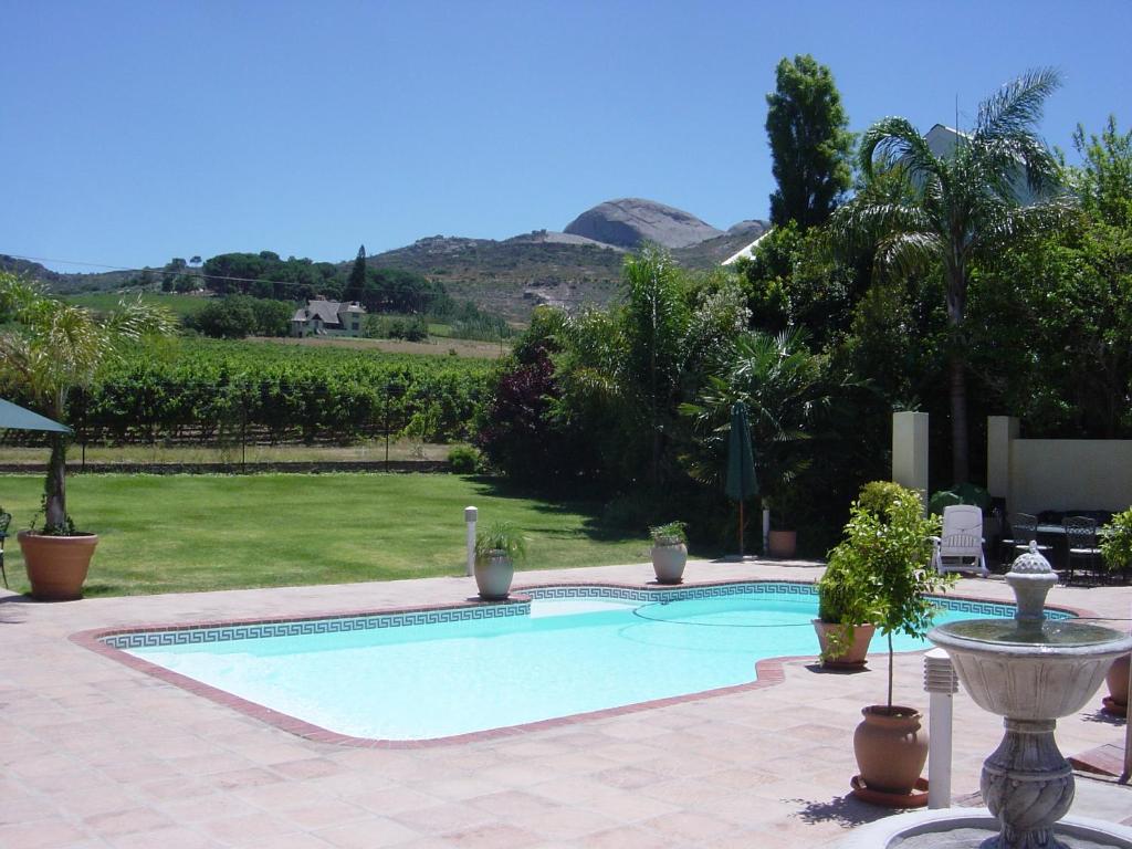 une grande piscine dans une cour avec des montagnes en arrière-plan dans l'établissement Oak Tree Lodge, à Paarl