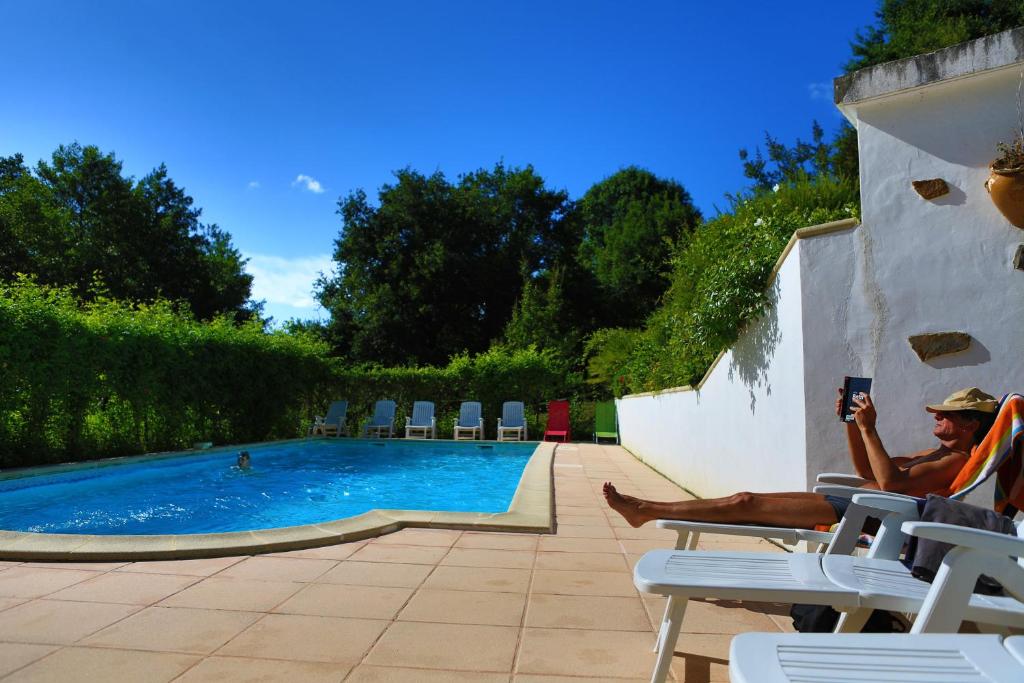 a man sitting in chairs next to a swimming pool at Les Chalets de Pierretoun in Labastide-Clairence
