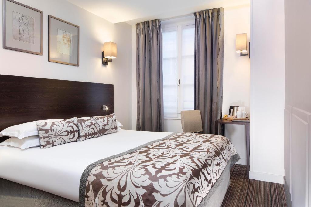 a hotel room with a large bed and a window at Hôtel Paris Louvre Opéra in Paris