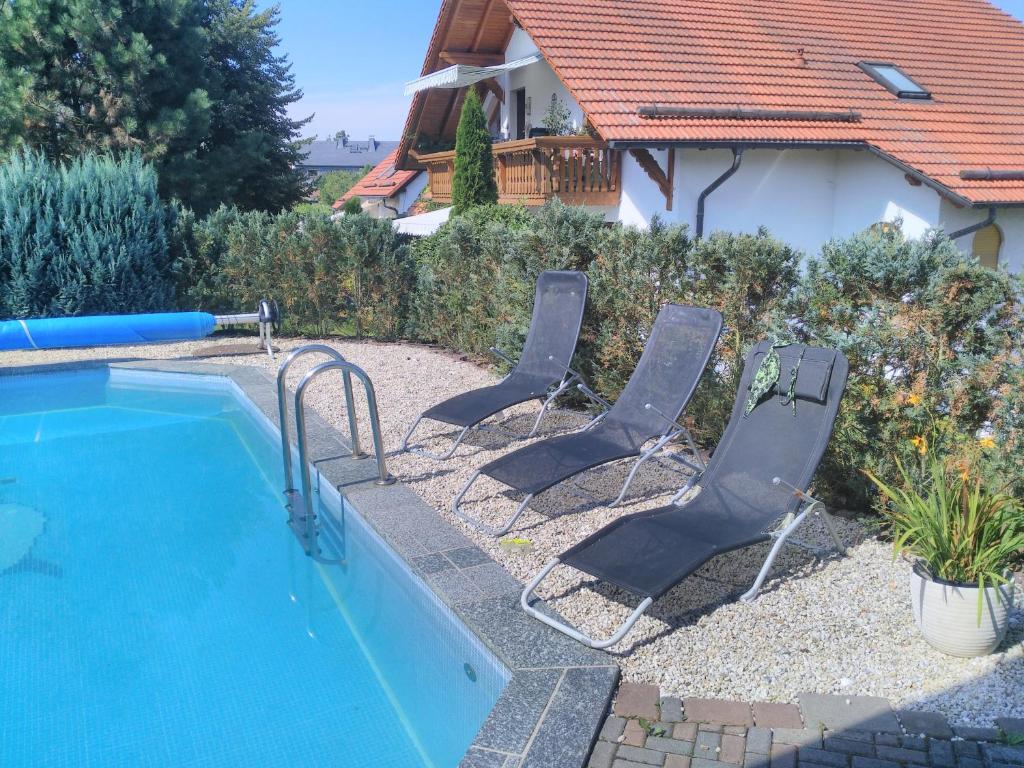 2 sillas y una piscina frente a una casa en Ferienwohnung und Pension Gürtler, en Mohlsdorf