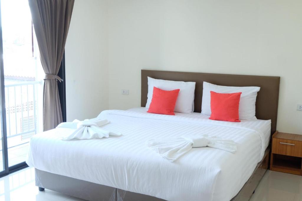 a bedroom with a large white bed with red pillows at DOS'S HOUSE in Nai Yang Beach