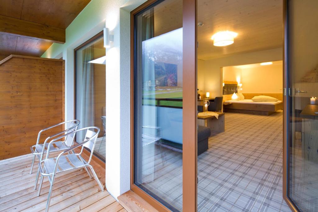 a balcony with a chair and a room with a bed at Hotel Bergland in Pertisau