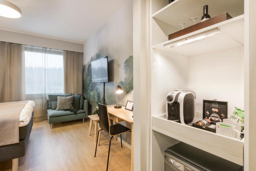 a hotel room with a bed and a desk and a room at Hotel Haaga Central Park in Helsinki