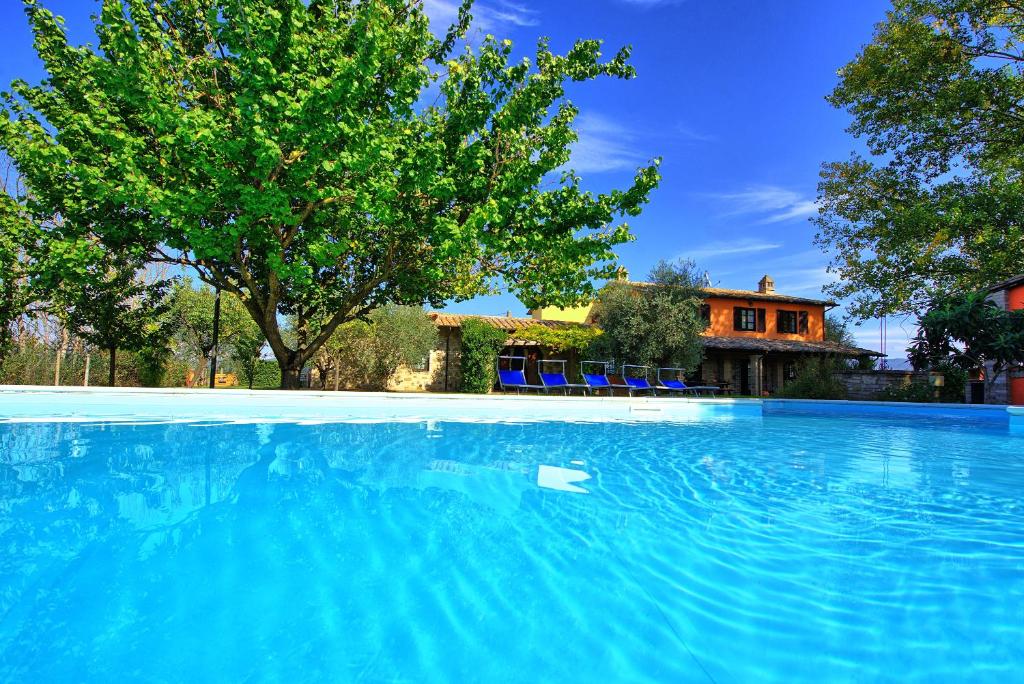 uma grande piscina azul em frente a uma casa em Villa Reale by PosarelliVillas em Assis