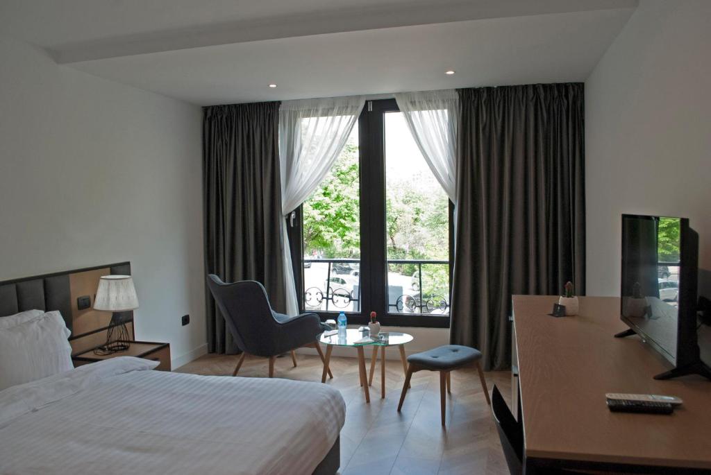 a hotel room with a bed and a desk and a tv at Prime Hotel in Tirana