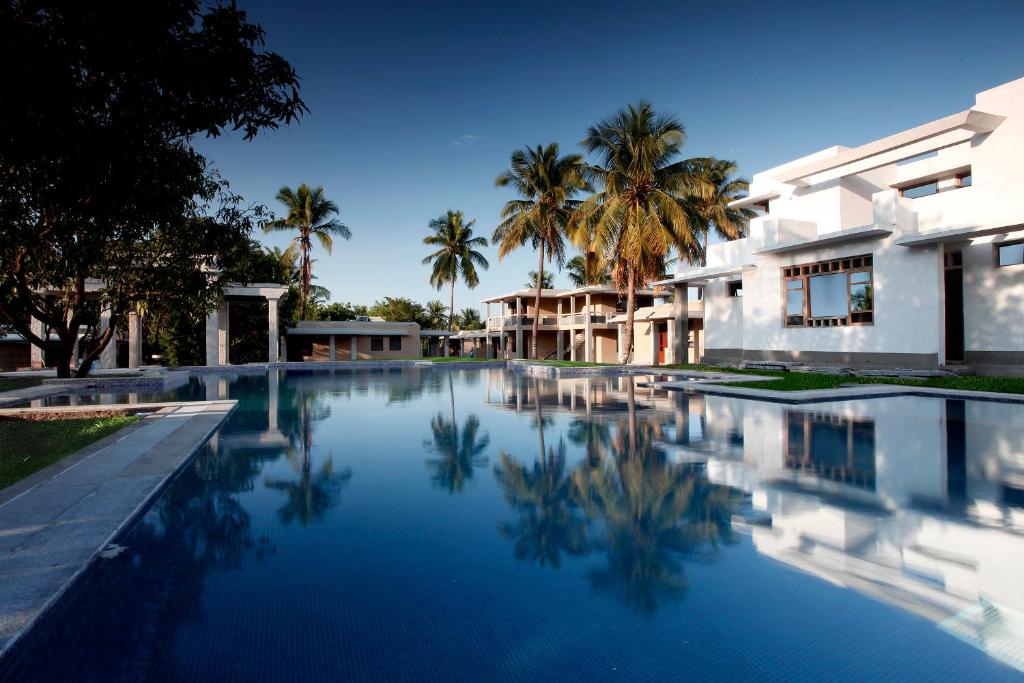 una piscina frente a una casa con palmeras en Heritage Resort Hampi, en Hampi