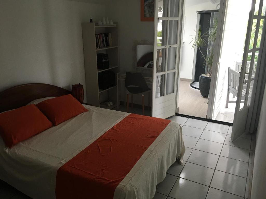1 dormitorio con 1 cama y puerta que da a un patio en Appart Cocotiers, en La Saline-Les-Bains