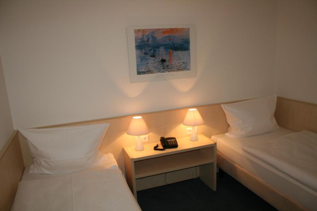 a hotel room with two beds and a phone on a night stand at Hotel am Bad in Esslingen