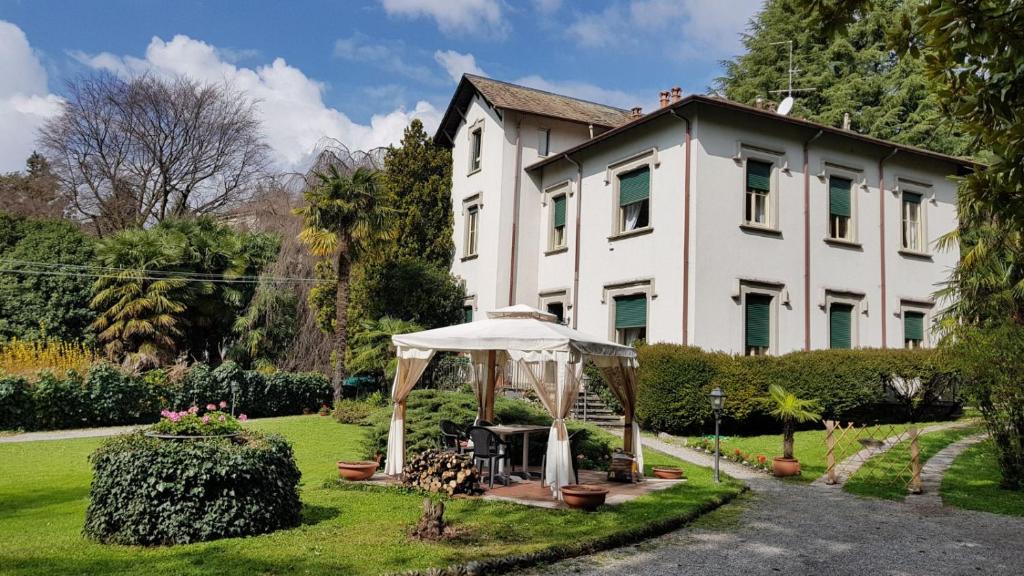 une maison blanche avec un parasol devant elle dans l'établissement Villa del Cigno, à Lecco