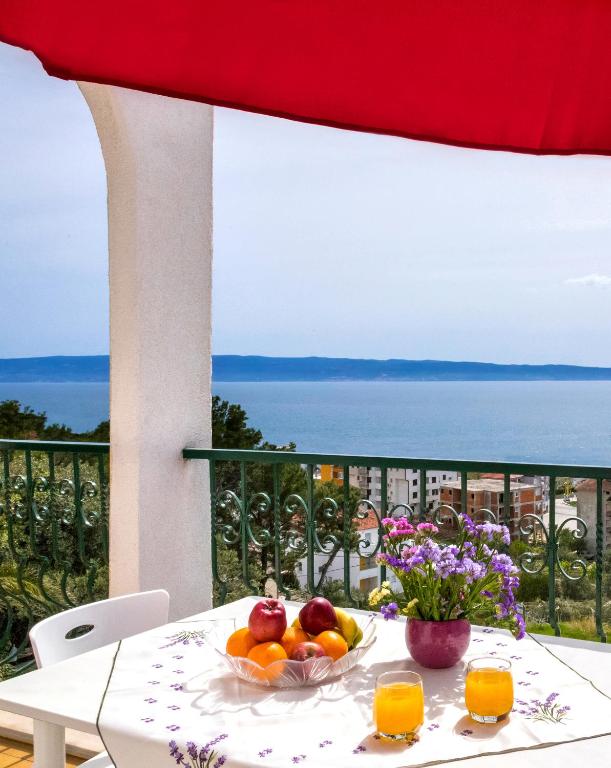 a table with fruit and flowers on a balcony at Apartmani AMI in Podstrana