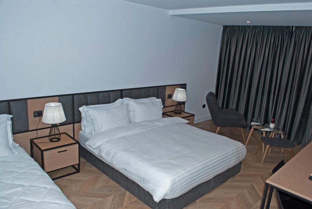 a hotel room with two beds and a chair at Prime Hotel in Tirana