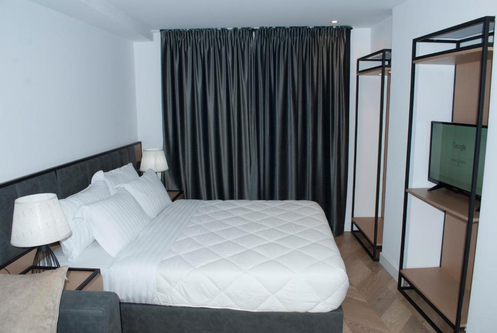 a bedroom with a white bed and a television at Prime Hotel in Tirana