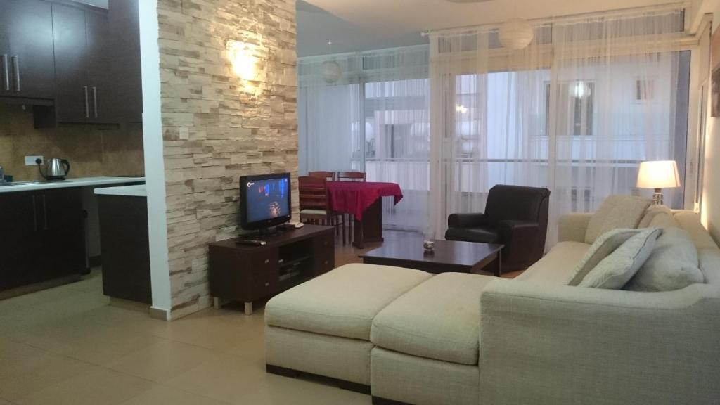 a living room with a couch and a tv and a kitchen at Aetius Apartments in Larnaca