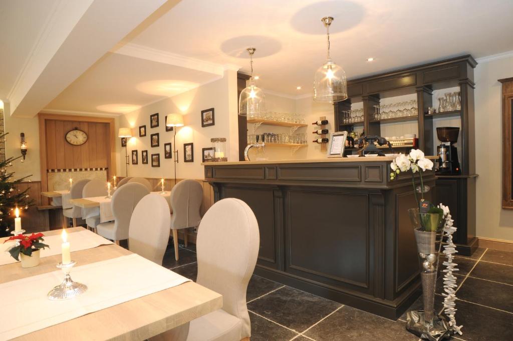 a dining room with a bar and a table and chairs at Hotel Eifelland in Butgenbach