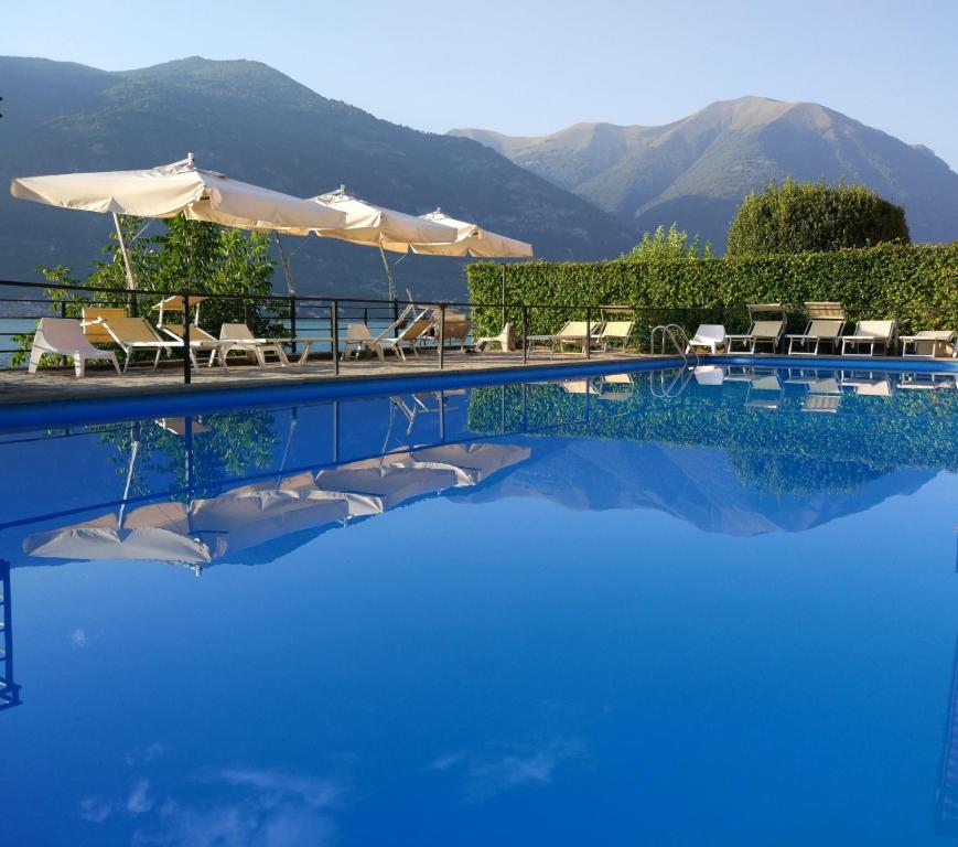 a swimming pool with chairs and umbrellas at Crotto del Misto in Lezzeno