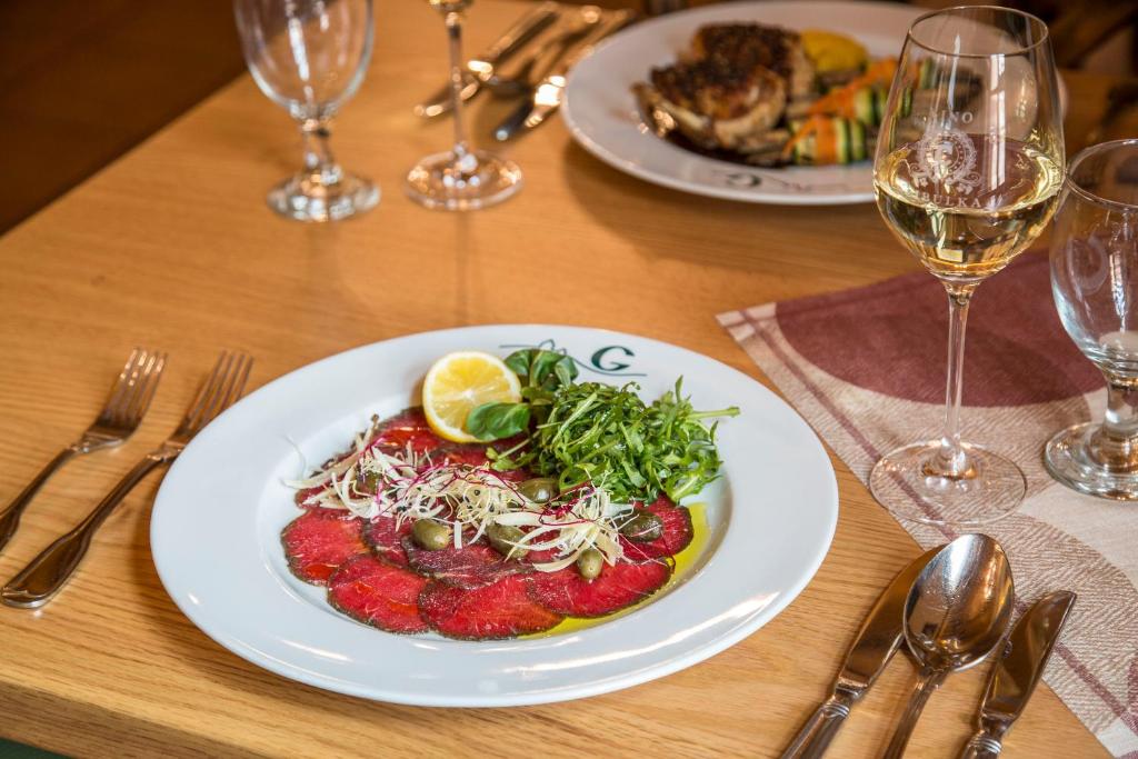 a plate of food on a table with wine glasses at Hotel Galant Lednice in Lednice