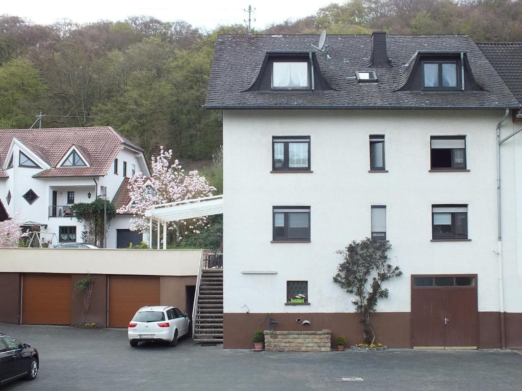 a white house with a car parked in a parking lot at Gästehaus Neises in Minden