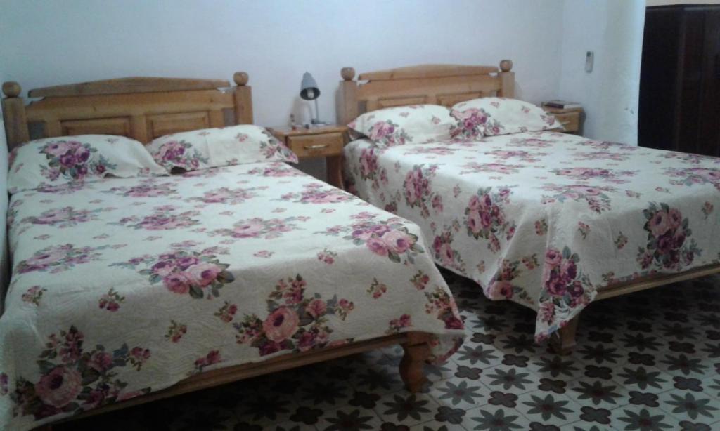 a bedroom with two beds with flowers on them at Hostal Trista 117 in Santa Clara
