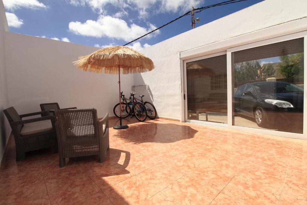 une terrasse avec une chaise, un parasol et une voiture dans l'établissement MONTAÑA VALLES DE ORTEGA -C, à Valles de Ortega