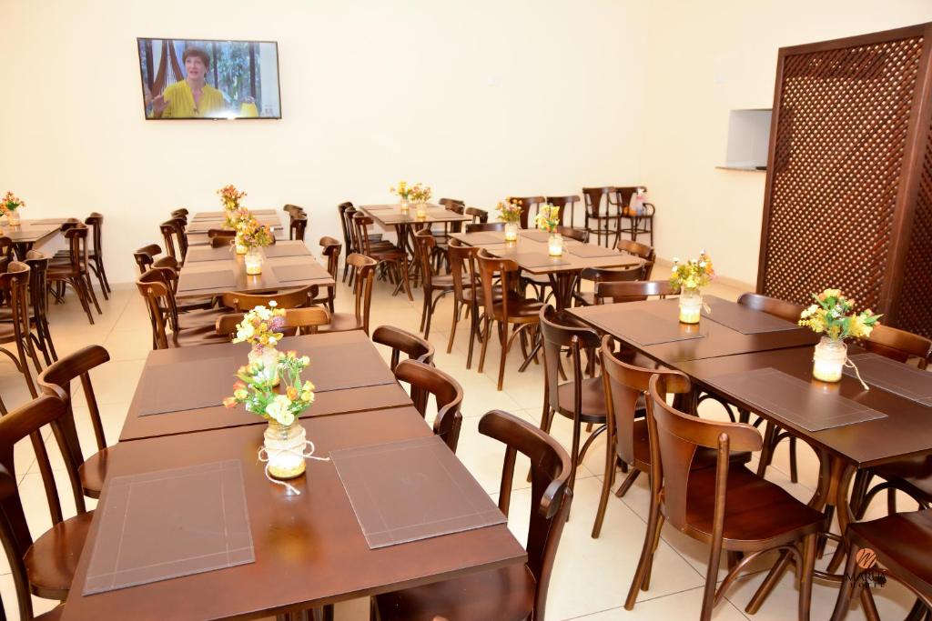 um restaurante com mesas de madeira e cadeiras com flores em Hotel Maruá em São José dos Campos