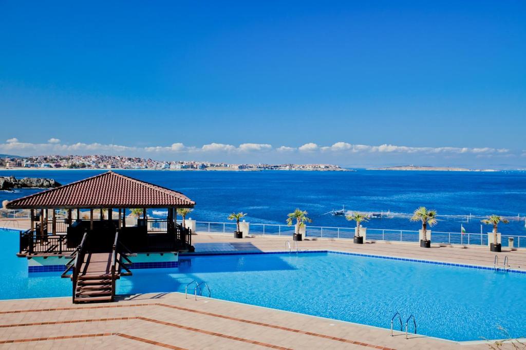 a swimming pool with the ocean in the background at Sozopolis Holiday Village in Sozopol