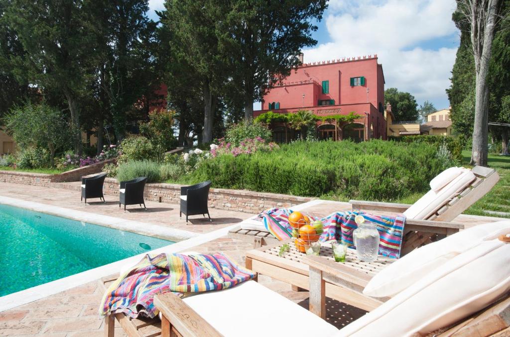 een patio met een tafel en stoelen naast een zwembad bij Tenuta Cambiano by PosarelliVillas in Castelfiorentino