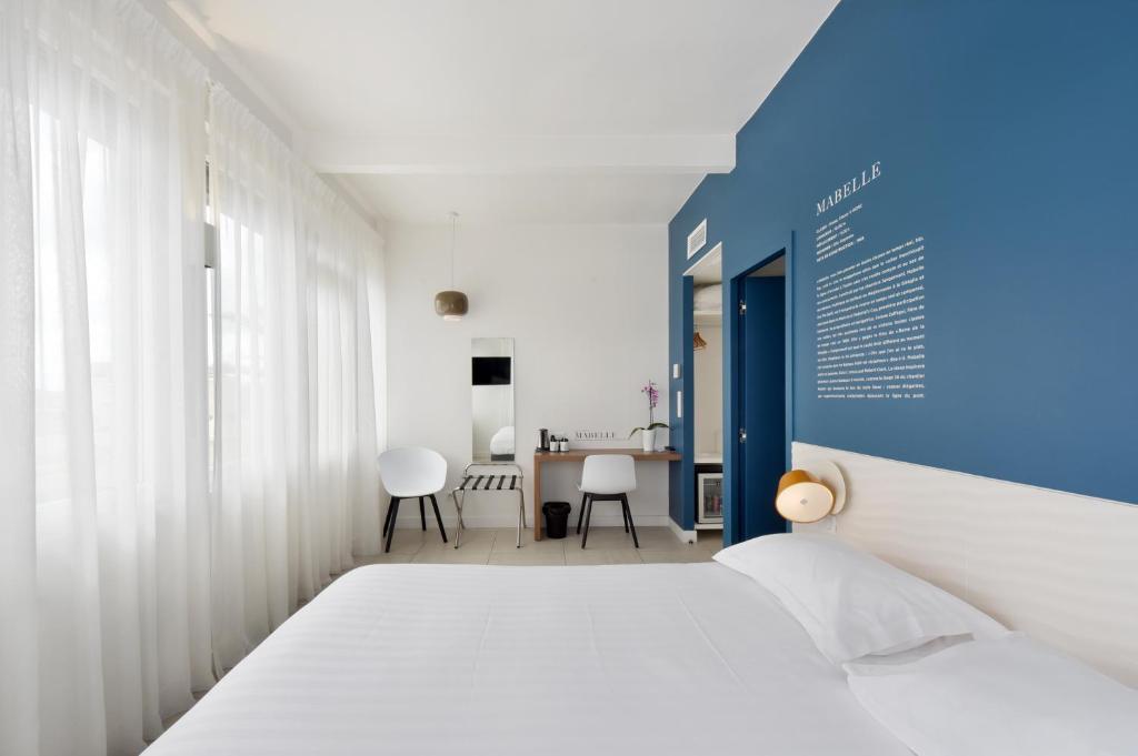 トゥーロンにあるオテル レ ヴェールのベッドルーム1室(ベッド1台、テーブル、椅子付)