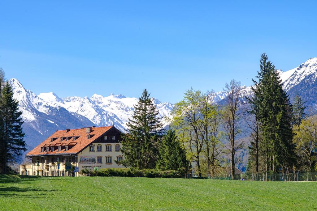 uma casa num campo com montanhas ao fundo em Hotel Grünwalderhof em Innsbruck