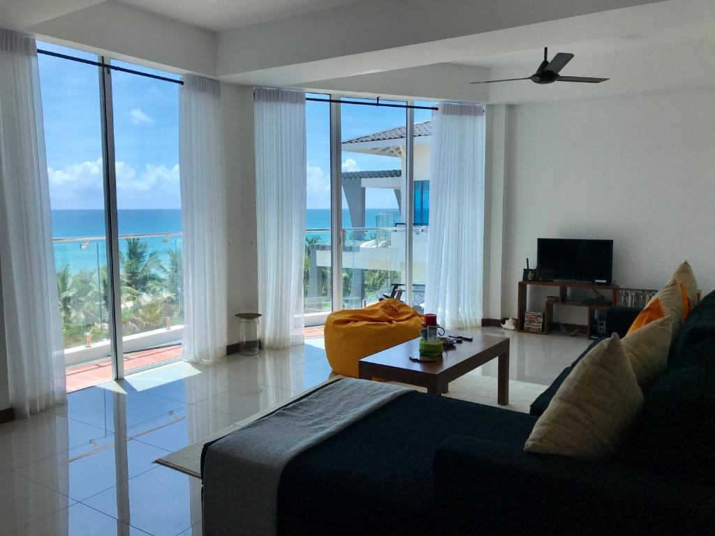 Sala de estar con cama y vistas al océano en Araliya OceanFront Condos Nilaveli, Trincomalee en Nilaveli