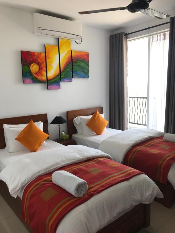 two beds in a room with paintings on the wall at Araliya OceanFront Condos Nilaveli, Trincomalee in Nilaveli