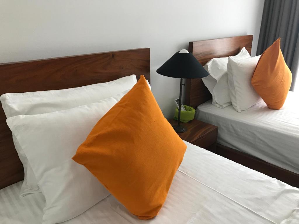 a hotel room with two beds with orange pillows at Araliya OceanFront Condos Nilaveli, Trincomalee in Nilaveli