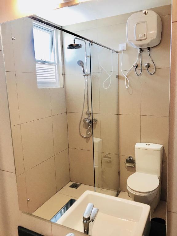 a bathroom with a shower and a toilet and a sink at Araliya OceanFront Condos Nilaveli, Trincomalee in Nilaveli