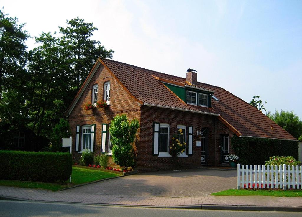a brown house with a white fence in front of it at Nordsee Haus An't Oll Deep in Dornumersiel