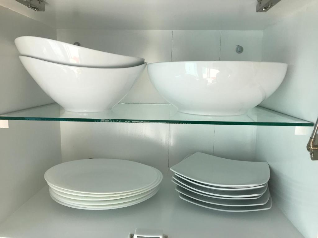 two bowls and plates on a glass shelf in a kitchen at Araliya OceanFront Condos Nilaveli, Trincomalee in Nilaveli