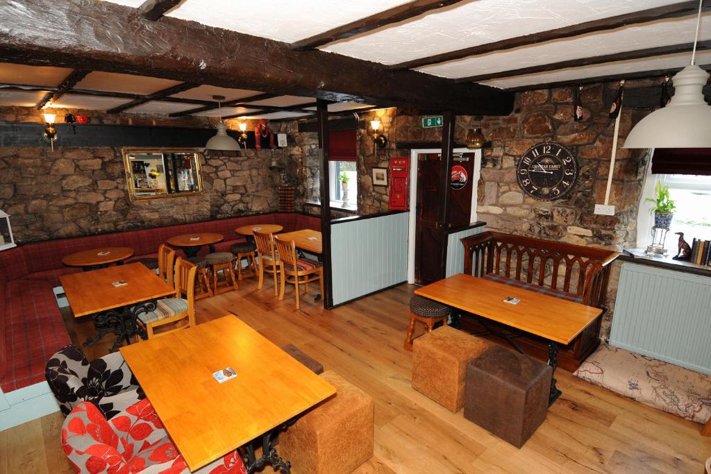 un restaurante con mesas de madera y sillas en una habitación en Old Posting House en Cockermouth