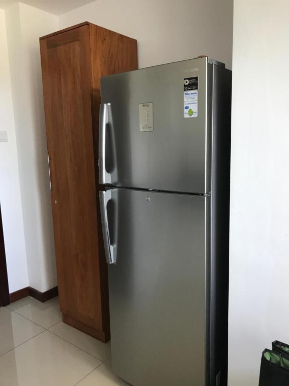 a stainless steel refrigerator next to a wooden door at Araliya OceanFront Condos Nilaveli, Trincomalee in Nilaveli
