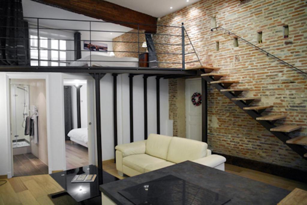 a living room with a couch and a brick wall at Atout Carmes in Toulouse