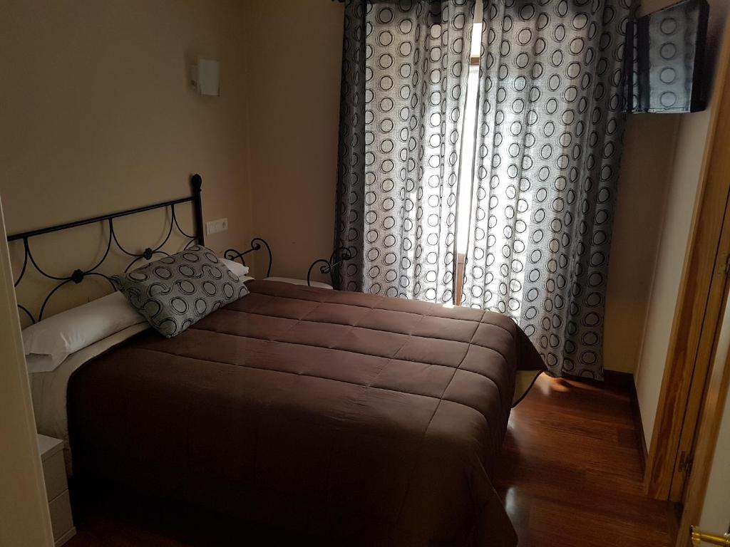 een slaapkamer met een groot bed en een raam bij Pensión Arenal in San Vicente de la Barquera