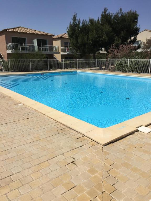 a large blue swimming pool in front of a house at Appartement dans Les jardins de Phoebus in Gruissan