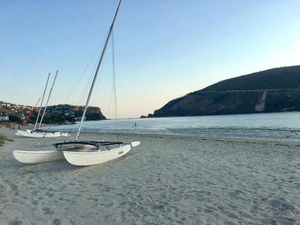 dos barcos sentados en una playa de arena cerca del agua en One on Bollard, en Knysna