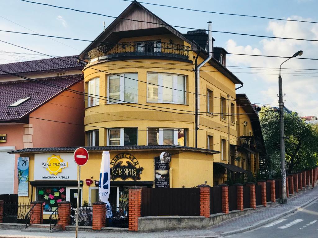 un bâtiment jaune sur une rue avec un panneau d'arrêt dans l'établissement Villa L'vovskaia, à Trouskavets