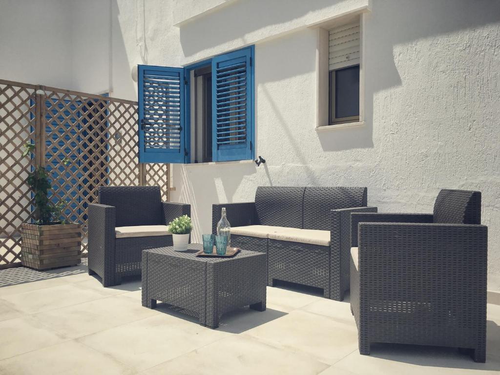patio con sedie in vimini, tavolo e finestre blu di SoleMareSalento Pt a Lido Marini