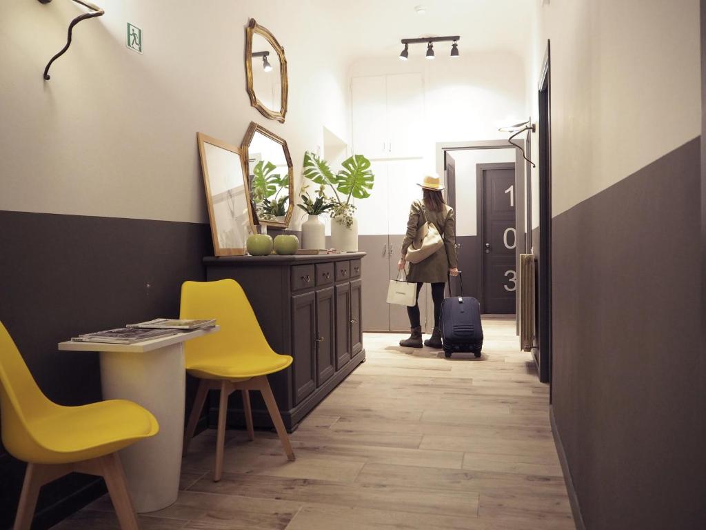 una donna che cammina lungo un corridoio con sedie gialle di Hotel Centro a Firenze