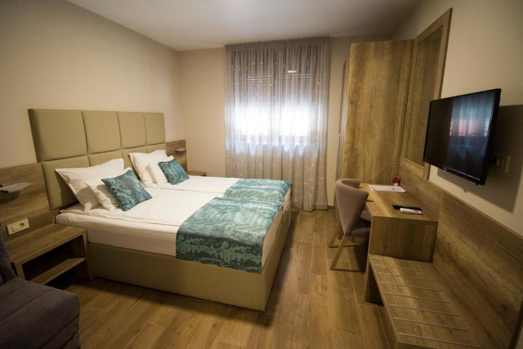 a hotel room with a bed and a flat screen tv at Villa Divani in Mostar