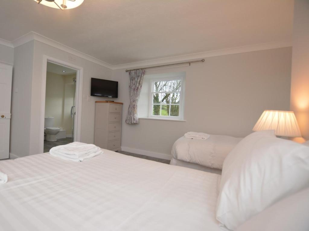 a white bedroom with a bed and a window at Pengarreg Fawr in Llanilar