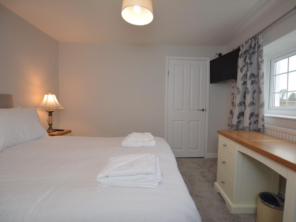 a bedroom with a bed and a desk and a window at Pengarreg Fawr in Llanilar