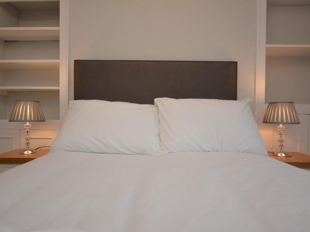 a bedroom with a white bed with two lamps at Pengarreg Fawr in Llanilar