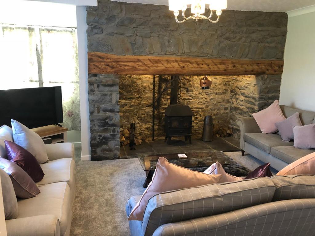 a living room with two couches and a stone fireplace at Pengarreg Fawr in Llanilar