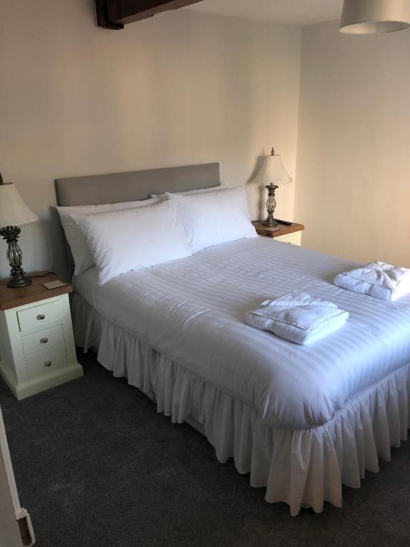 a bedroom with a large bed with white sheets and two lamps at Pengarreg Fawr in Llanilar